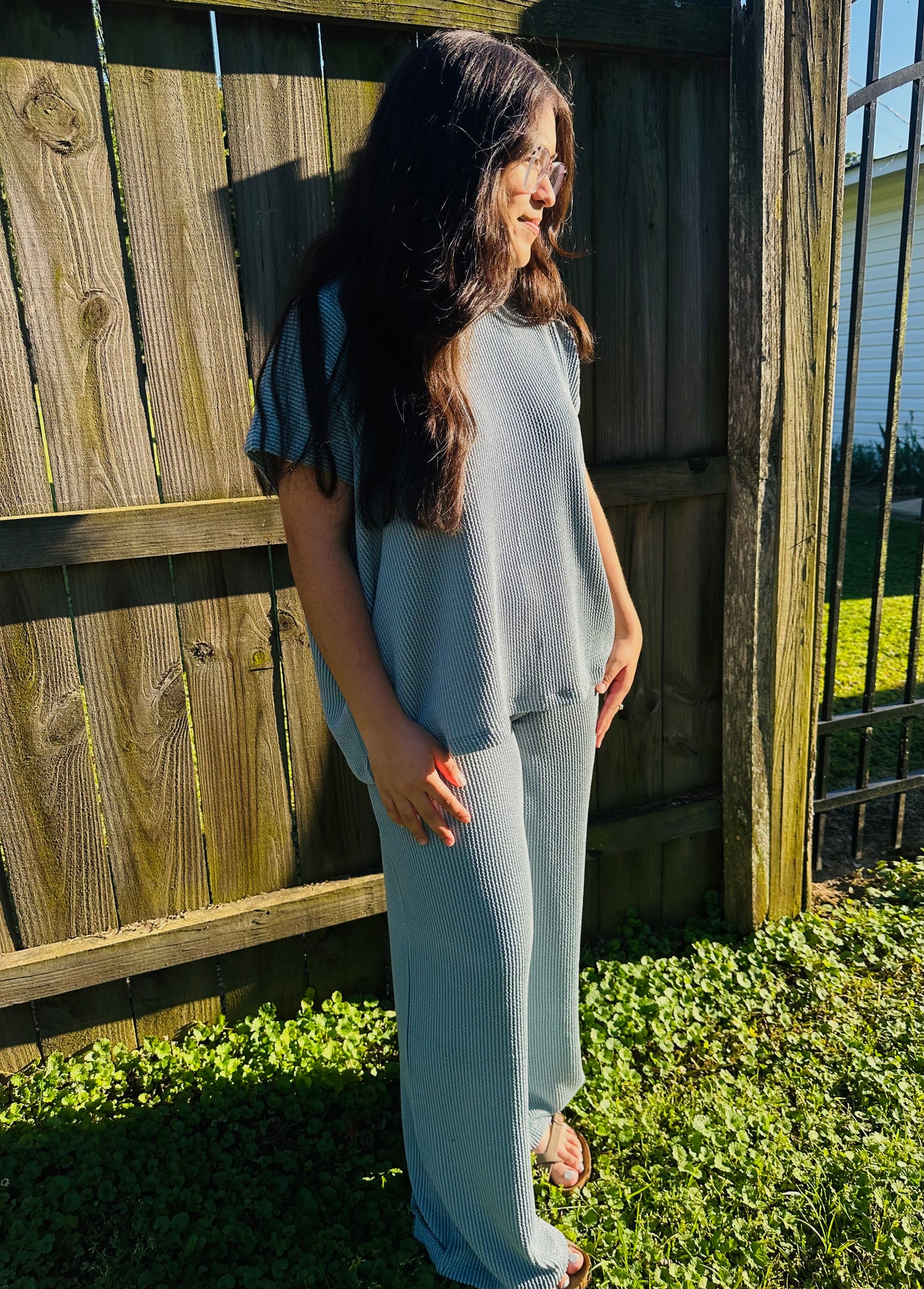 Model wearing a light blue ribbed lounge set featuring a loose short-sleeve top and wide-leg pants, photographed outdoors.
