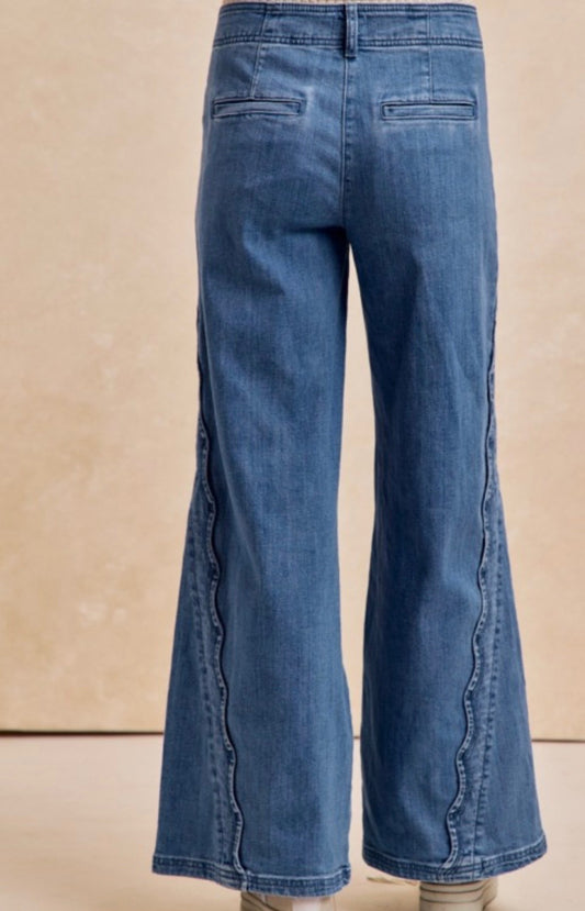 Blue jeans with a beige background and wavy deatil on both side of jeans.