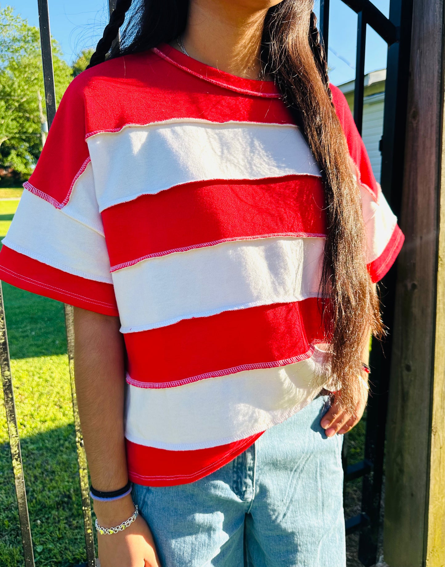 Red and white vertical Stripped shirts in outdoor background with grass and a fence in the back.