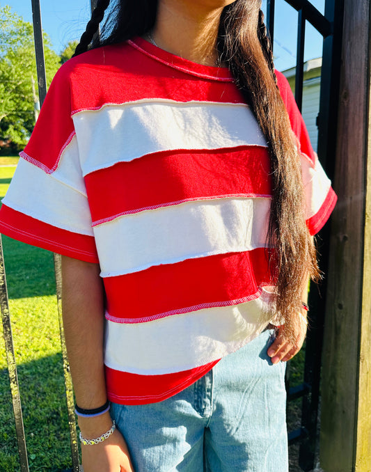 Red and white vertical Stripped shirts in outdoor background with grass and a fence in the back.