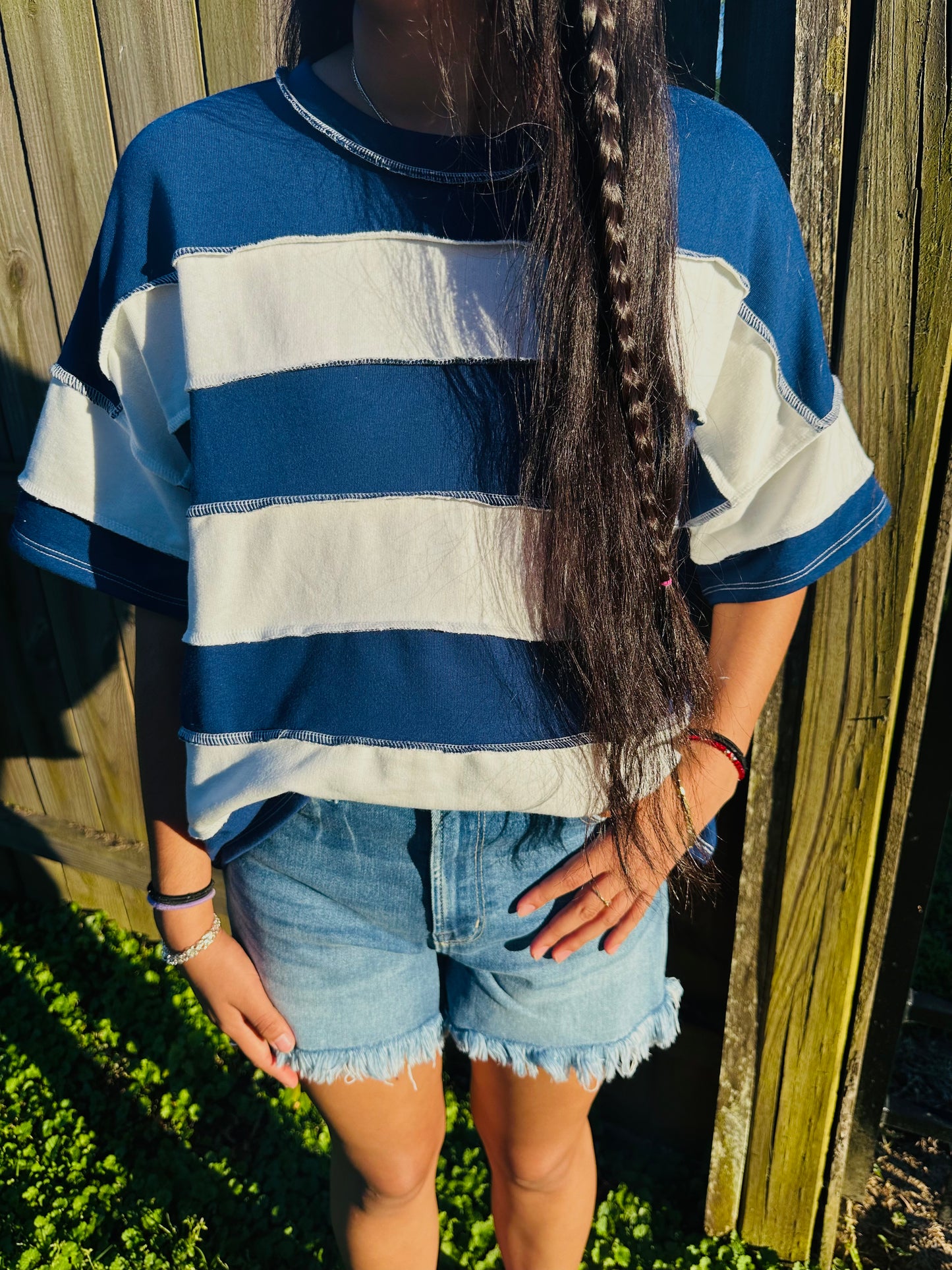 Blue and white vertical Stripped shirts in outdoor background with grass and a fence in the back.
