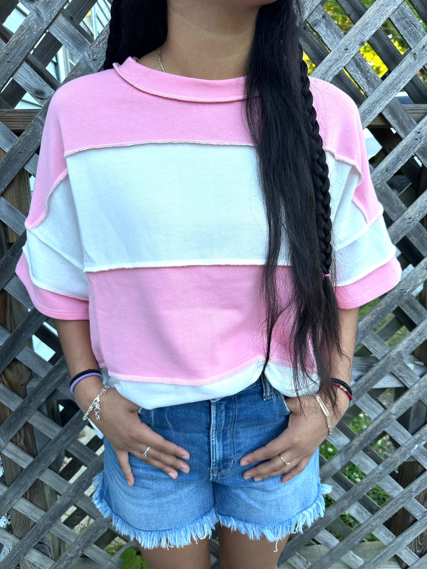 Pink and white vertical Stripped shirts in outdoor background with grass and a fence in the back.