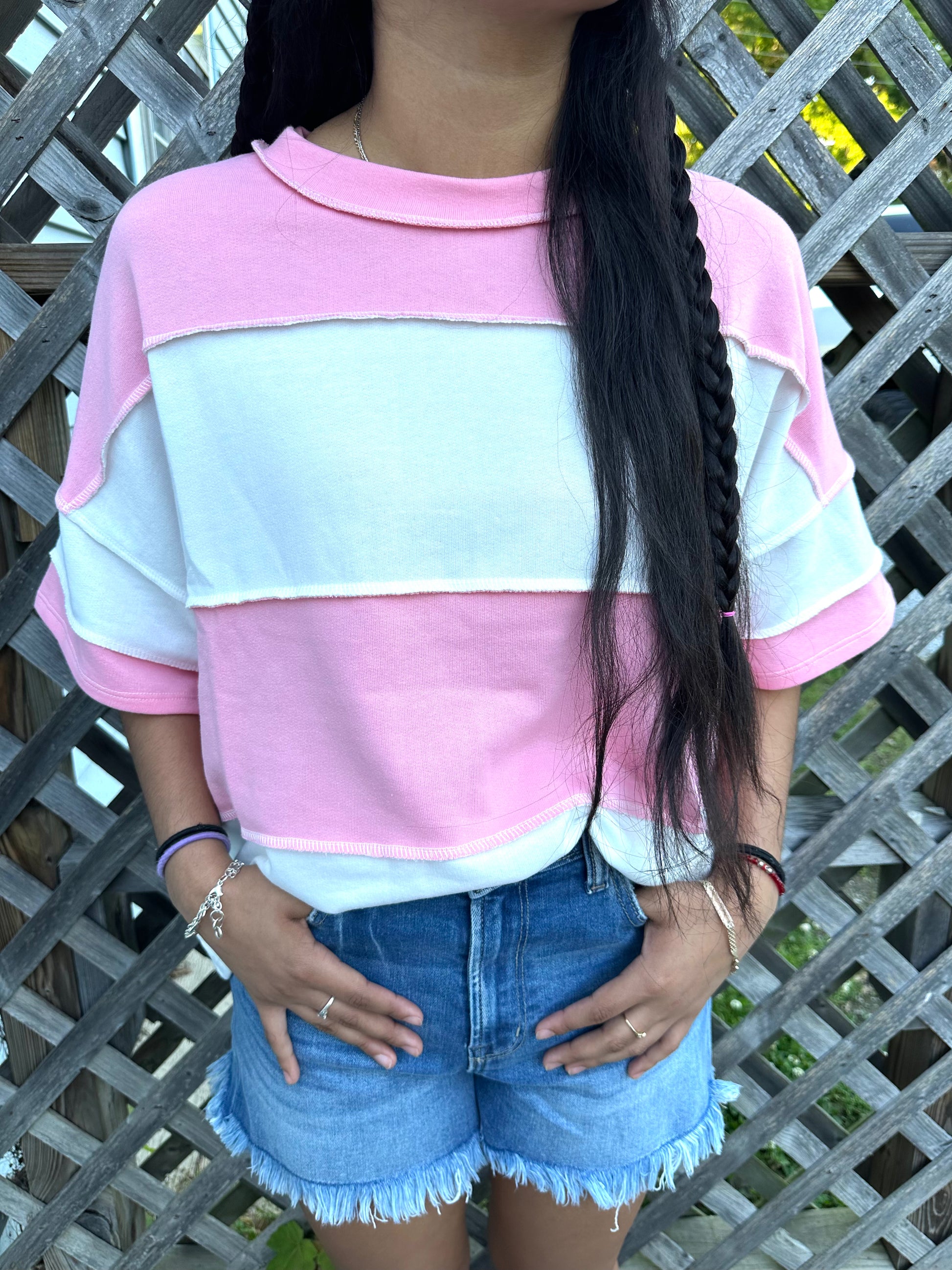 Pink and white vertical Stripped shirts in outdoor background with grass and a fence in the back.