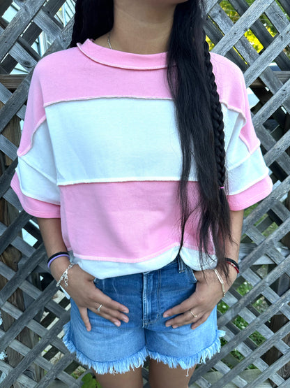 Pink and white vertical Stripped shirts in outdoor background with grass and a fence in the back.