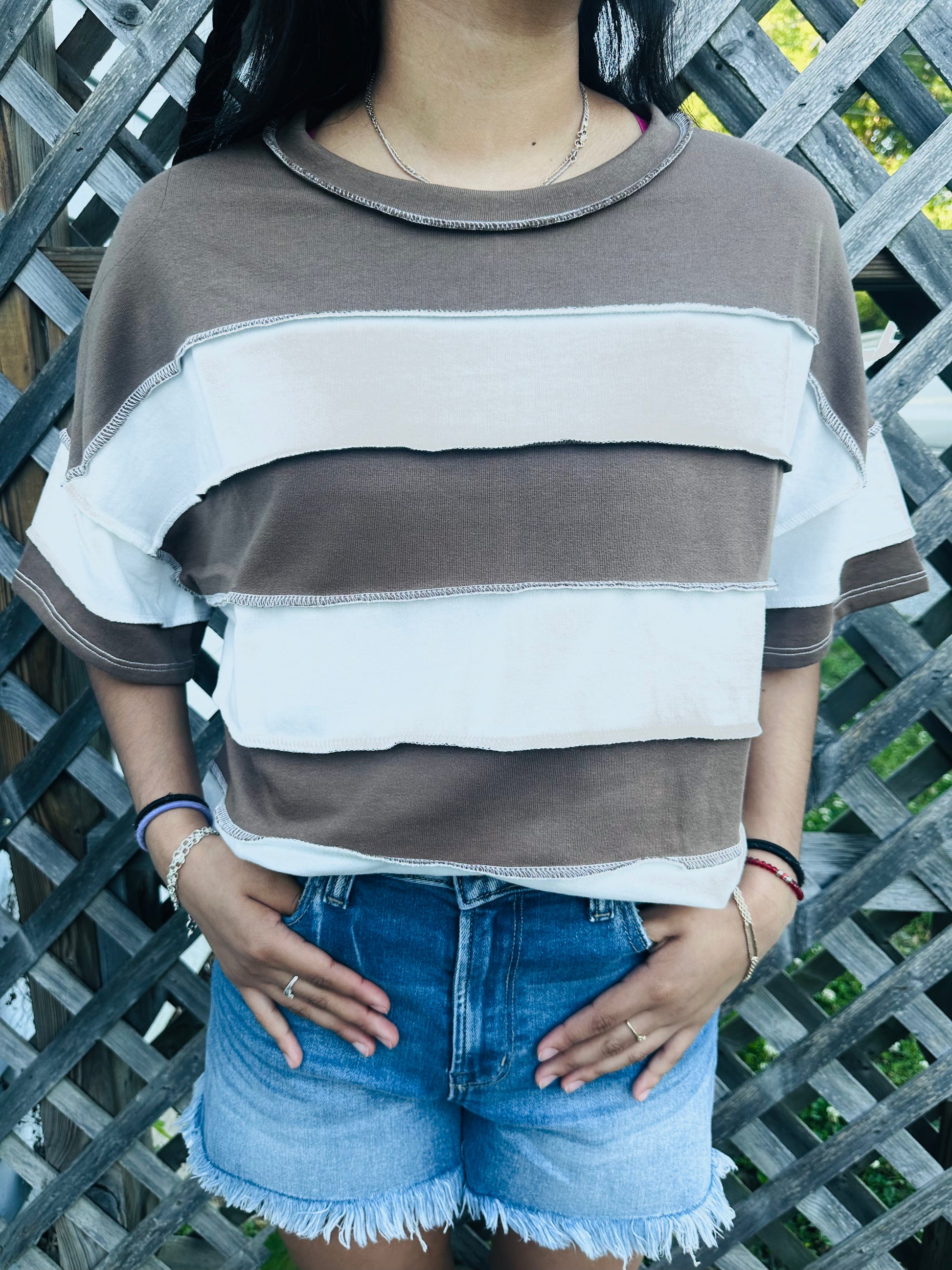 Brown and white vertical Stripped shirts in outdoor background with grass and a fence in the back.